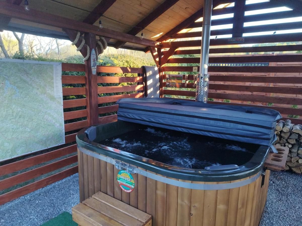 Jacuzzi z bąbelkami pod drewnianym dachem altany, obok drewno