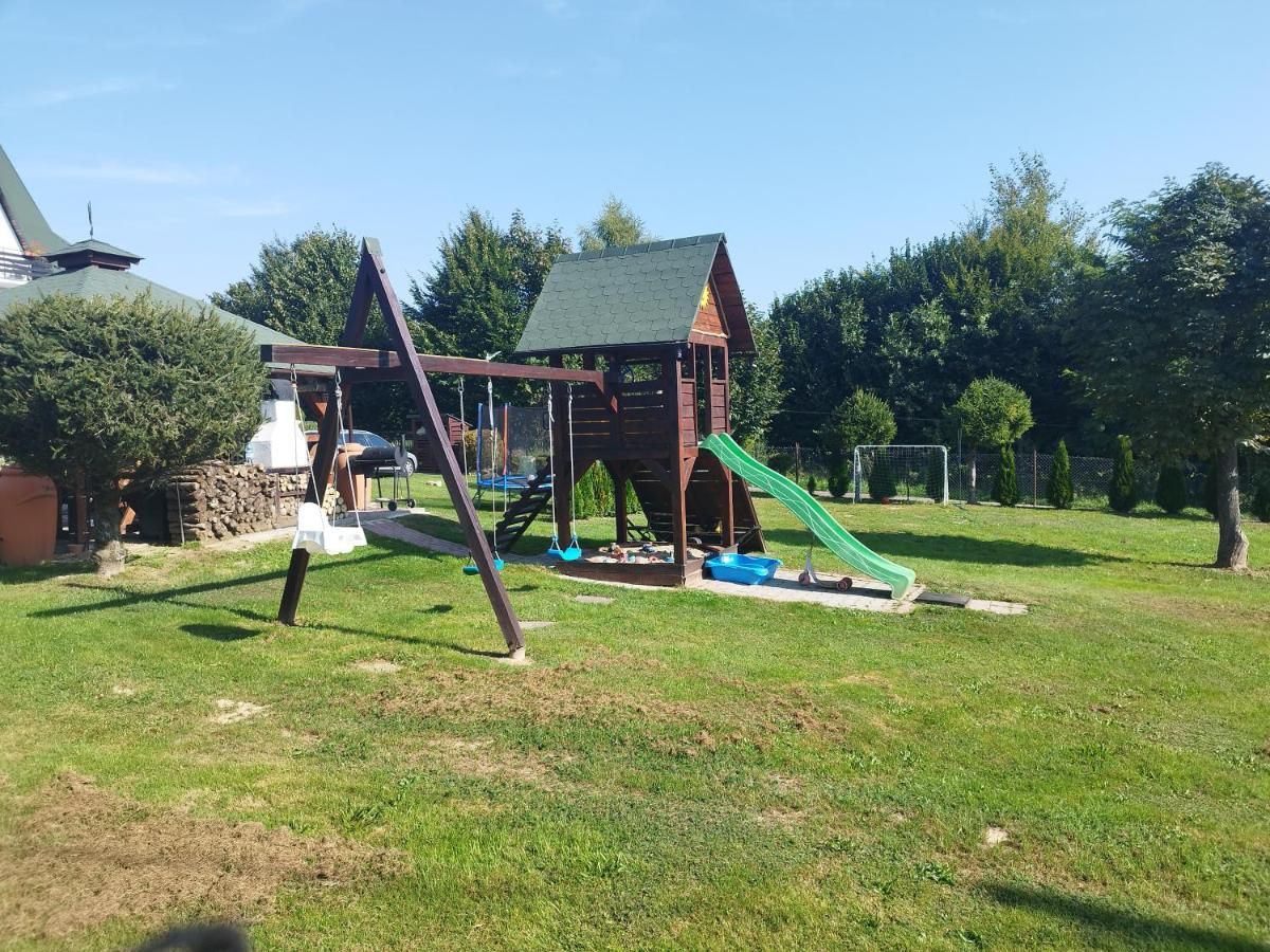Plac zabaw ze zjeżdżalnią, huśtawkami i piaskownicą na trawie